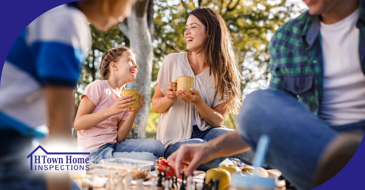 Mother and daughter sharing a laugh while enjoying hot drinks outdoors with family