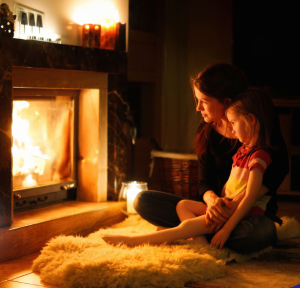 Mother and child sitting by a cozy fireplace during winter.