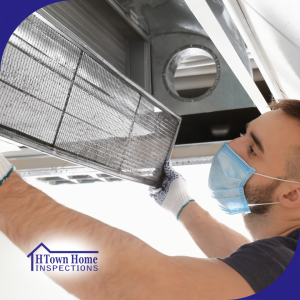 A technician wearing a protective face mask and gloves inspects or replaces an air filter in an HVAC system.