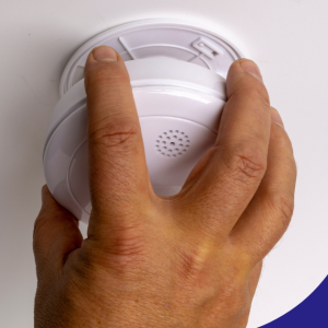 Hand installing a ceiling-mounted smoke and carbon monoxide detector