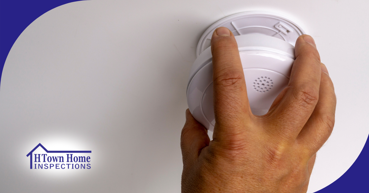 Hand installing a ceiling-mounted smoke and carbon monoxide detector