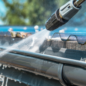 Water jet cleaning a house gutter.