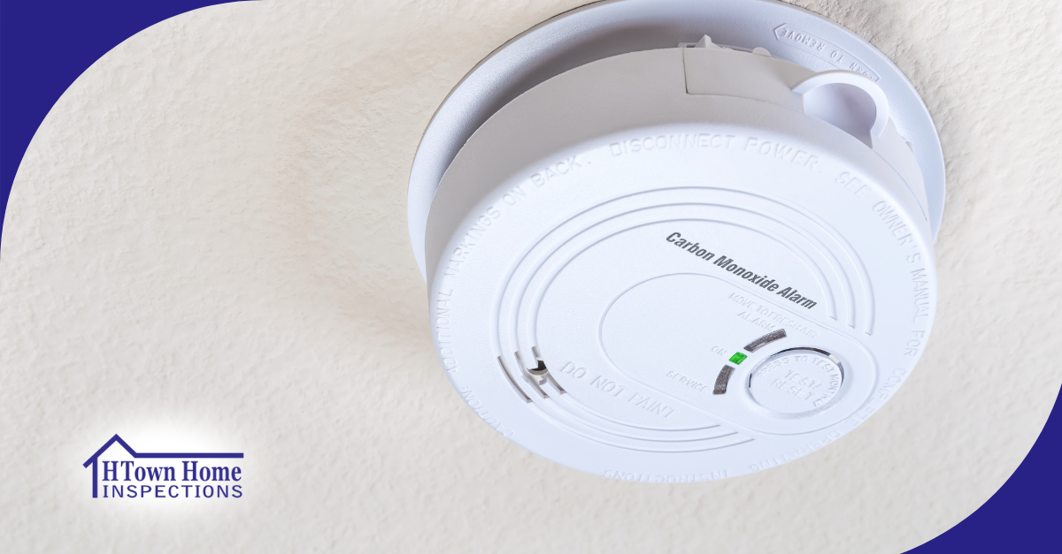 A carbon monoxide alarm on the ceiling with a green indicator light